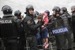 A Slovenian police officer pulls a crying girl out of a crowd of refugees waiting to cross the border after most of them spent a night in front of the border station of Rigonce, Slovenia, Saturday, Sept. 19, 2015.