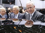 In this May 5, 2015 file photo Volkswagen CEO Martin Winterkorn, right, is reflected at the roof of a car during a tour around a fair hall prior to the annual shareholder meeting of the car manufacturer Volkswagen in Hannover, Germany.