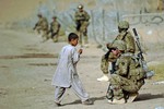 File - Alaskan National Guard Sgt. Brain Reid talks with a local Afghan child during a dismounted patrol to a Department of Public Works facility Aug. 8, 2012, in Kandahar, Afghanistan.