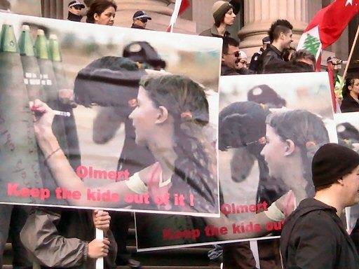 Placards with news images of children writing on artillery shells