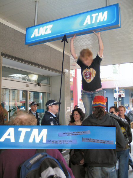 Protester attches anti-war stickers to ANZ sign