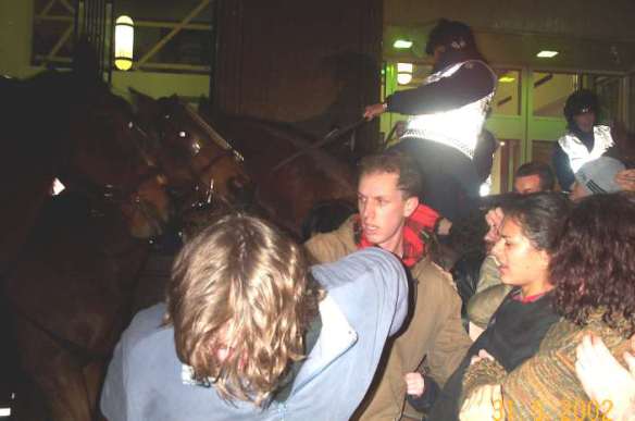 Closeup of protesters being pushed aside by horses