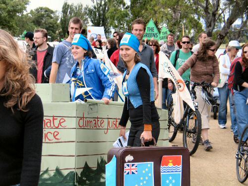 FoE 'boat' and activist with suitcases carrying flags of Pacific nations