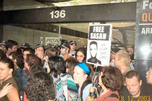 Police and blockaders struggle;  placard: Free Sasan