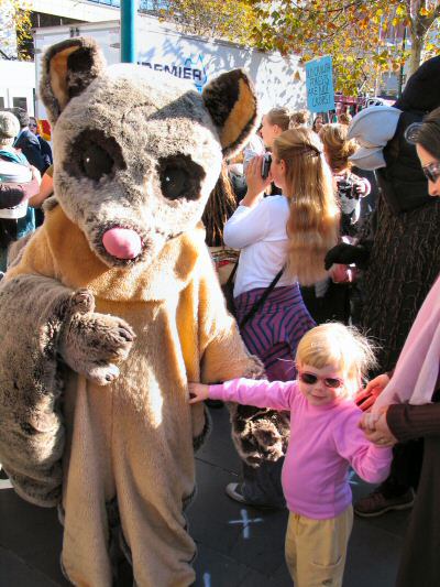 Child with protester in possum costume