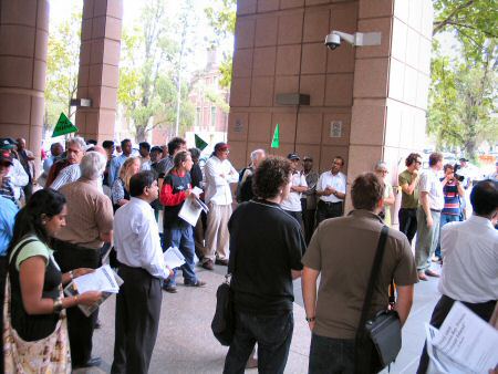 Protesters in the forecourt, watched by camera high on wall