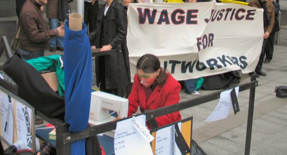 Another view of machinist with banner in backgound  - Wage Justice for Outworkers