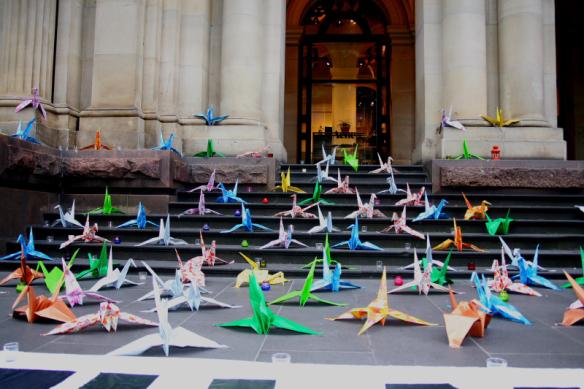 Origami cranes and candles on steps leading from GPO