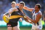 Ben Cunnington gets hold of Dustin Martin's guernsey in a bid to prevent him from disposing of the ball.