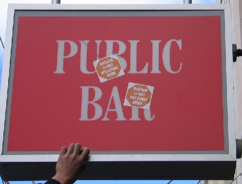 Stickers on the pub sign - Racism is not welcome here