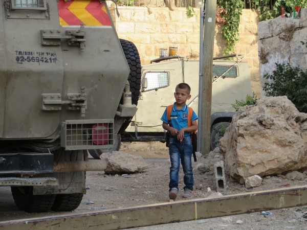 Small boy forced to pass Israeli forces' armored trucks