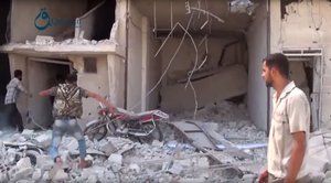 In this Thursday, Oct. 1, 2015, image taken from video provided by the Syrian activist-based media group Qasioun News, which has-been verified and is consistent with other AP reporting, Syrians gather near the rubble of a building, in the aftermath of a Russian airstrike, in Dair al-Asafeer village, rural Damascus, Syria.