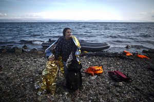 A Syrian refugee woman and child are wrapped with thermal blankets to shelter from the cold after arriving on a dinghy from the Turkish coast to the northeastern Greek island of Lesbos, Friday, Oct. 2 , 2015.