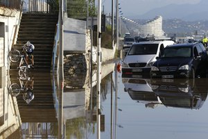 A man carrying his bicycle tries to make his way after floods in Biot, near Cannes, southeastern France, Sunday Oct.4, 2015. Sudden heavy rains around the French Riviera have killed at least 16 people.