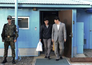 In this photo provided by the South Korean Unification Ministry, South Korean Won Moon Joo, center, who has permanent resident status in the United States, is escorted  by a South Korean official at the border village of Panmunjom in Paju, South Korea, Monday, Oct. 5, 2015. North Korea freed a South Korean national who'd been attending New York University before his detention, Seoul officials said Monday, in a possible sign Pyongyang wants better ties with rival Seoul and may back away from a recent threat to launch a long-range rocket later this month. (The South Korean Unification Ministry via AP)