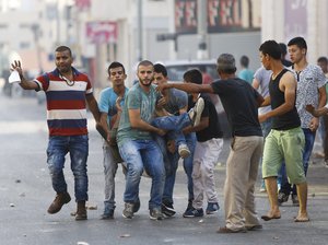 Palestinians carry an injured man during an Israeli military raid in the West Bank city of Jenin, Sunday, Oct. 4, 2015.