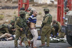 Israeli soldiers arrest a man while others treat Palestinians wounded during clashes with the Israeli military, near Ramallah, West Bank, Wednesday, Oct. 7, 2015.