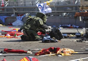 A bomb disposal officer inspects a suspected suitcase that proved to be empty at the scene of an explosion in Ankara, Turkey, Saturday, Oct. 10, 2015.