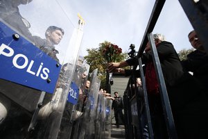 A protester offers carnations to Turkish police blocking the way to the site of Saturday's explosions in Ankara, Turkey, Sunday, Oct. 11, 2015.