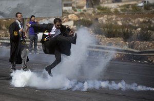 A lawyer wearing his official robes kicks a tear gas canister back toward Israeli soldiers during a demonstration by scores of Palestinian lawyers called for by the Palestinian Bar Association in solidarity with protesters at the Al-Aqsa mosque compound in Jerusalem's Old City, near Ramallah, West Bank, Monday, Oct. 12, 2015.