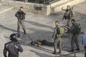 Israeli police stand around a Palestinian shot after he allegedly tried to stab a person at Damascus Gate of the Jerusalem's Old City, Wednesday, Oct. 14, 2015, Israeli police said.