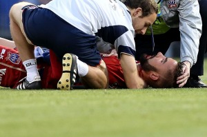 Mark Birighitti lays prone after the challenge from Sydney FC striker Shane Smeltz.