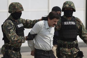 File - Joaquin "El Chapo" Guzman is escorted to a helicopter in handcuffs by Mexican navy marines at a navy hanger in Mexico City, Saturday, Feb. 22, 2014.