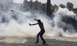 A Palestinian demonstrator uses a slingshot during clashes following a demonstration in the West Bank city of Ramallah, Monday, Oct. 5, 2015.