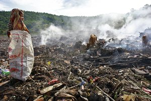 File - An East Timorese girl searches for food and clothing in a municipal garbage dump, Dili, Timor-Leste, 9 January, 2009. Residents are exposed to fumes from burning the rubbish as the crusher no longer works. The waste has to be temporarily burnt, creating toxic fumes.