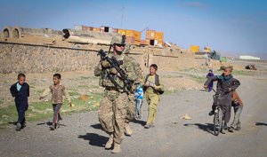 File - A U.S. Soldier, center, with Forward Support Company, 65th Engineer Battalion walks with Afghan children during a presence patrol in Kandahar province, Afghanistan, March 26, 2014.