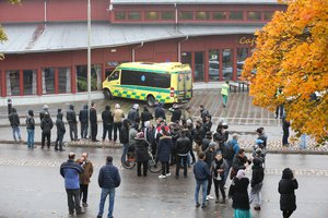 A crowd gathers outside, as emergency services attend the scene of a sword attack by a masked man at the Kronan school in Trollhattan, Sweden, Thursday Oct. 22, 2015.