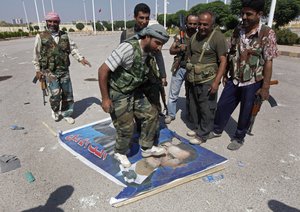 In this Saturday, Sept. 22, 2012 file photo, a Free Syrian Army fighter from the Al-Faruk brigade, center, steps on a portrait of Syrian President Bashar Assad, at the Tal Abyad, a Turkish-Syrian border crossing captured by the rebels earlier in the week, eastern Syria.