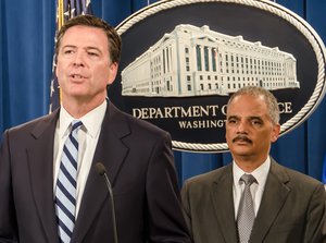 File - As Attorney General Eric Holder (right) looks on, FBI Director James Comey speaks at a press conference announcing charges against BNP Paribas, which has agreed to plead guilty and pay $8.9 billion for illegally processing financial transactions on behalf of countries subject to U.S. economic sanctions.