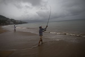 Mike Anderson of Minnesota, right, fishes alongside his friend and local fisherman Miguel Pilas during a steady rain as Hurricane Patricia approaches Puerto Vallarta, Mexico, Friday, Oct. 23, 2015.