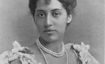 B&W photo of Indian woman in Edwardian evening dress, hair up, pearls.