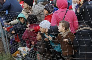 Migrants push on fence while waiting to enter a camp in Spielfeld, Austria, Sunday, Oct. 25, 2015.