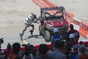 RoboSimian, a simian-inspired robot from the Jet Propulsion Labs, exits a vehicle during the Defense Advanced Research Projects Agency (DARPA) Robotics Challenge (DRC) June 5, 2015, in Pomona, California.