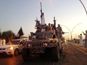 File - In this photo taken Monday, June 23, 2014, fighters from the Islamic State group parade in a commandeered Iraqi security forces armored vehicle down a main road at the northern city of Mosul, Iraq.