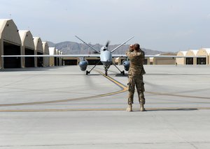 An Airman assigned to the 451st Expeditionary Aircraft Maintenance Squadron marshals an MQ-9 Reaper to the runway prior to launch March 20, 2015, at Kandahar Airfield, Afghanistan.