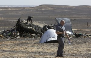 A Russian investigator walks near wreckage a day after a passenger jet bound for St. Petersburg, Russia, crashed in Hassana, Egypt, on Sunday, Nov. 1, 2015.