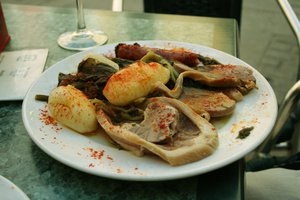 "Lacón con grelos", a typical Galician dish: pork shoulder ham with rapini, along with steamed potatoes and a sausage.