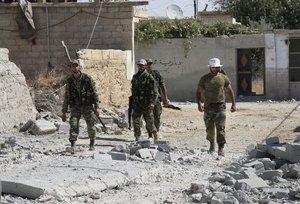 File - In this photo taken on Sunday, Oct. 11, 2015, Syrian army soldiers walk in Achan, Hama province, Syria.