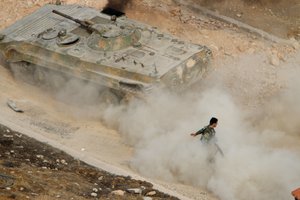 A Syrian APC moves raising dust in Harasta, northeast of Damascus, Syria, Thursday, Oct. 22, 2015. 