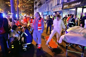 People rest on a bench after being evacuated from the Bataclan theater after a shooting in Paris, Saturday, Nov. 14, 2015.