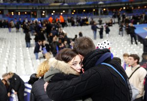 Spectators embrace each other as they stand on the playing field of the Stade de France stadium at the end of a friendly soccer match between France and Germany in Saint Denis, outside Paris, Friday, Nov. 13, 2015.