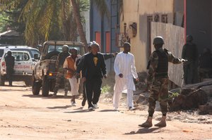 Security forces, right, escort people from the Radisson Blu hotel were gunmen attacked in Bamako, Mali, Friday, Nov. 20, 2015.