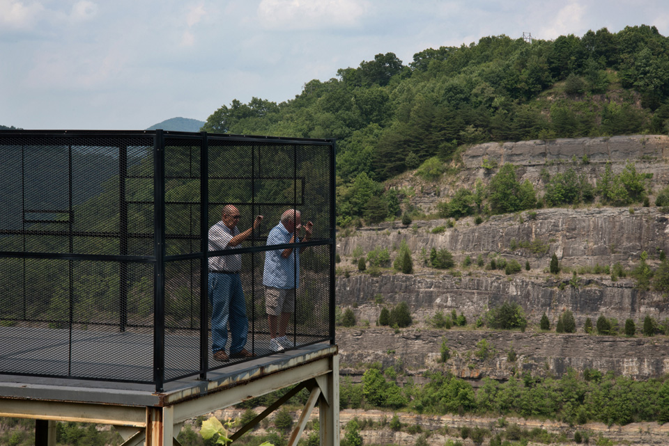 Men standing in cage overlooking mine