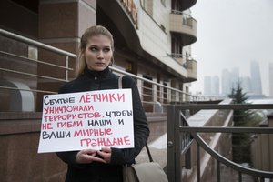 A woman holds a poster as she pickets the Turkish Embassy in Moscow, Russia, Tuesday, Nov. 24, 2015.