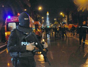 A hooded police officer prevents media from aproaching the scene of a bus explosion in the center of the capital, Tunis, Tunisia, Tuesday, Nov. 24, 2015.