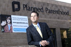 In this photo taken Sunday, Jan. 23, 2011, Bryan Howard, President and CEO of Planned Parenthood Arizona, Inc., poses in front of a Planned Parenthood facility in Tucson, Ariz.